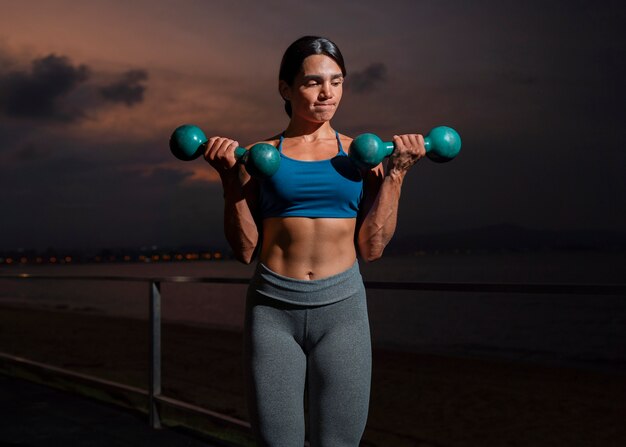 Front view fit woman training with dumbells