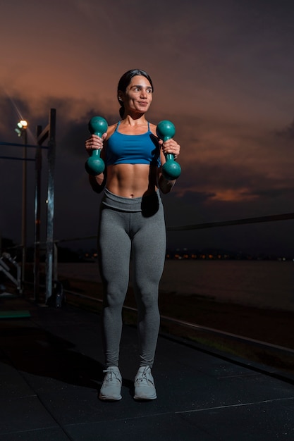 Front view fit woman training with dumbells