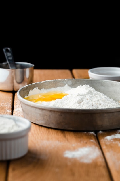 Free photo front view of flour and egg on wooden table