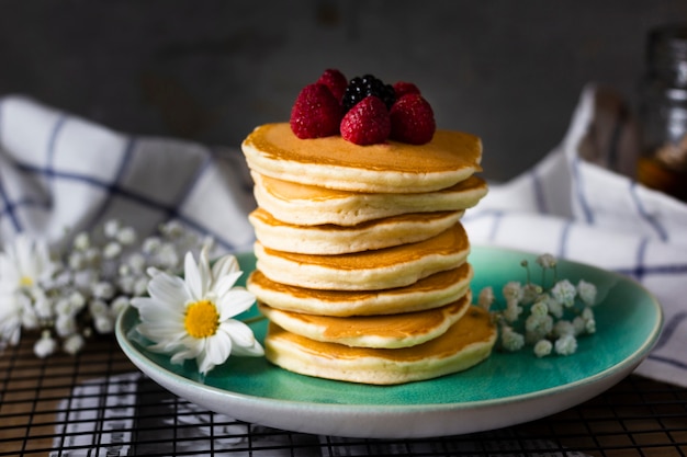 Front view fluffy pancakes with forest fruits on plate
