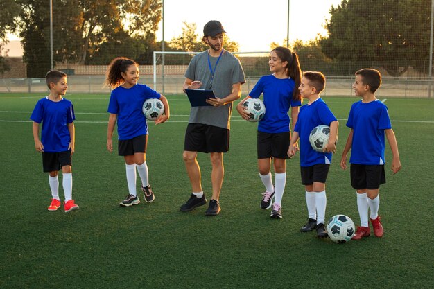 フィールドで子供たちを教える正面図サッカー トレーナー