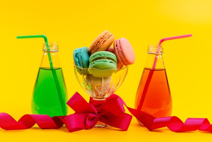 Free Photo a front view french macarons along with colored drinks with straw on yellow, cake sweet biscuit