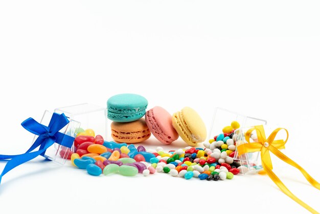 A front view french macarons along with colorful candies on white, biscuit cake color