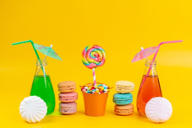 A front view french macarons along with meringues and cocktails on yellow, cake biscuit color