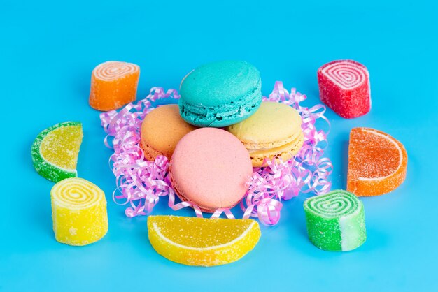 A front view french macarons colorful sweet yummy along with confitures on blue