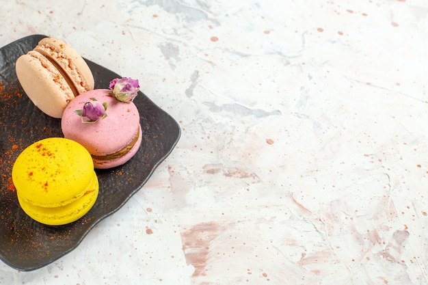 Front view french macarons inside plate on the white table biscuit sweet cake