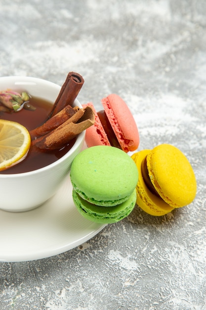 Front view french macarons with cup of tea on white surface cake biscuit sweet dessert bake pie cookie