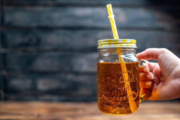 木製の机の上のストローで缶の中の新鮮なリンゴ ジュースを正面から見た図