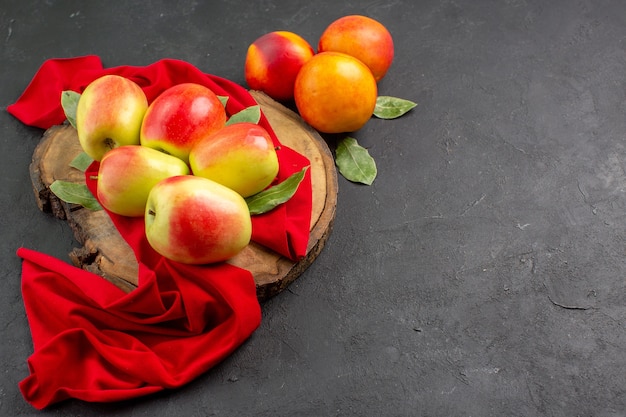 暗いテーブルの色の新鮮な熟した果樹に桃と新鮮なリンゴの正面図