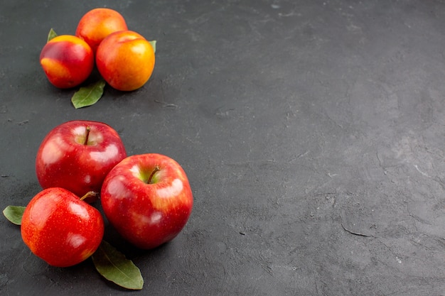 暗いテーブルの色の新鮮な熟した果実に桃と新鮮なリンゴの正面図