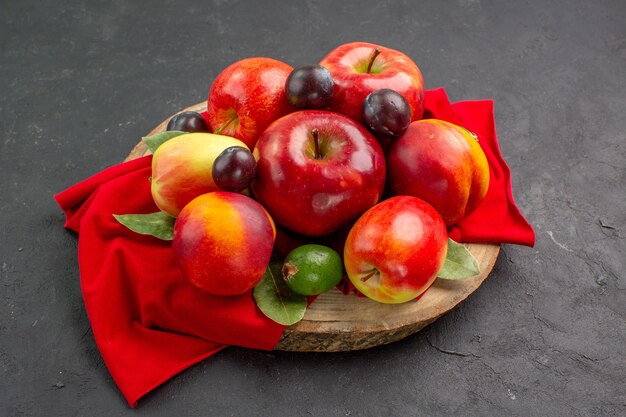 暗い机の上の桃とプラムと新鮮なリンゴの正面図熟したまろやかなジュースの木