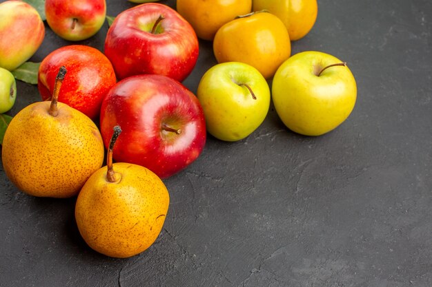 Вид спереди свежие яблоки с грушами и хурмой на темном столе, свежее спелое спелое дерево
