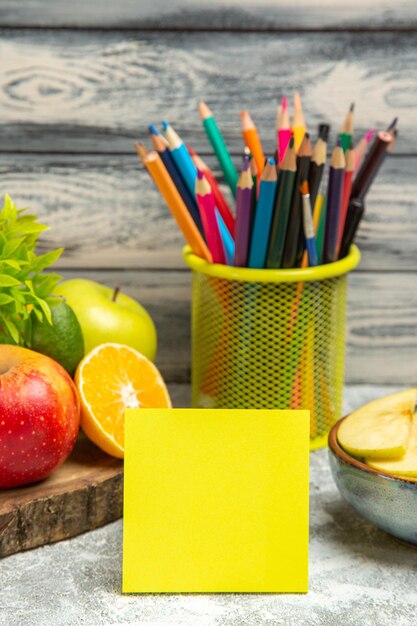 Front view fresh apples with sliced oranges and pencils on the grey background ripe mellow fruit fresh apple