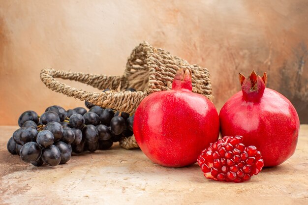 Front view fresh black grapes with pomegranates on light background mellow photo tree ripe fruit vitamine