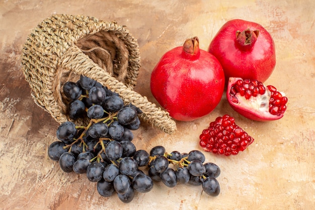 Front view fresh black grapes with pomegranates on the light background ripe fruit mellow photo tree vitamine