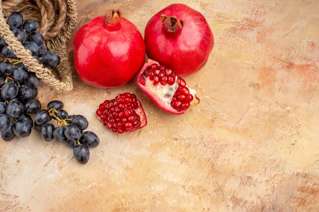 Front view fresh black grapes with pomegranates on light background ripe fruits mellow photo tree vitamine