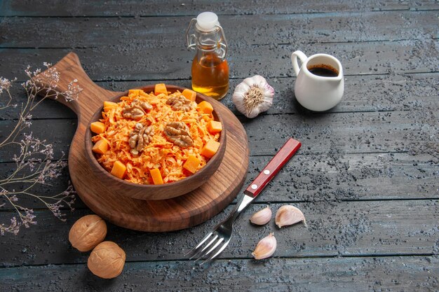 Салат из свежей моркови, вид спереди, тертый салат с грецкими орехами на темном столе, диетический цветной ореховый салат для здоровья