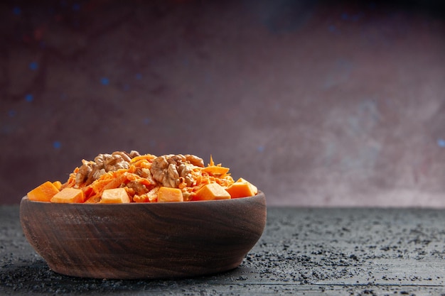 Салат из свежей моркови, вид спереди, тертый салат с грецкими орехами и чесноком на темном столе, диетический салат, цвет орехов, здоровье