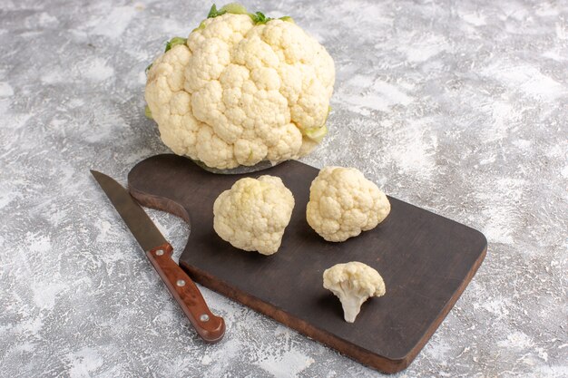 Front view of fresh cauliflower with knife and on the light-white wall