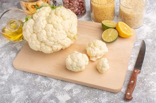 Front view of fresh cauliflower with lemon and oil on the white-light backgruond vegetable food meal raw color