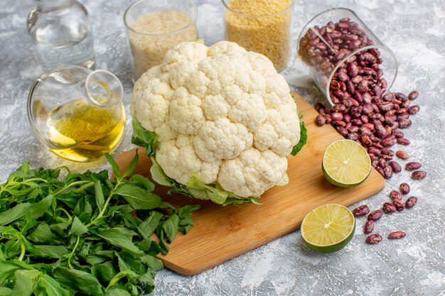 Front view of fresh cauliflower with oil greens and beans on the grey desk