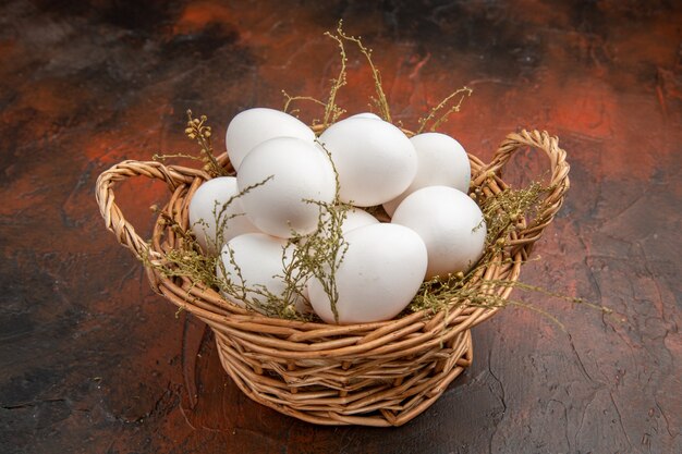 Front view fresh chicken eggs inside basket on dark surface