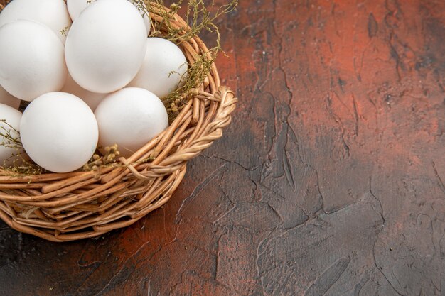 Front view fresh chicken eggs inside basket on dark surface