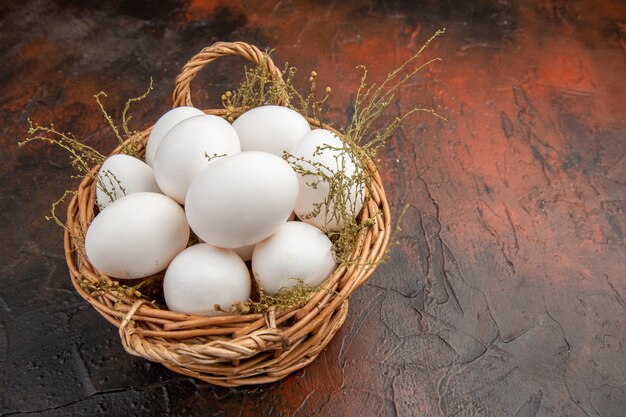 Front view fresh chicken eggs inside basket on the dark surface