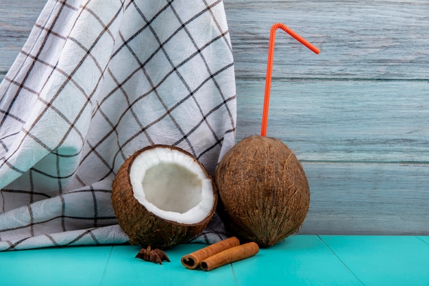 Вид спереди свежих кокосов с оранжевой соломой на проверенной скатерти на серой поверхности