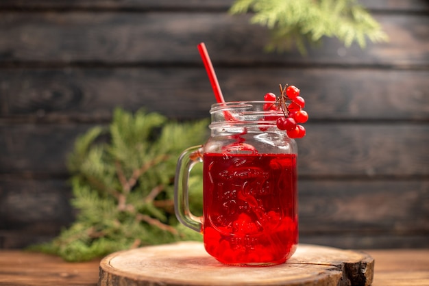 Front view of fresh currant juice in a glass served with tube on a wooden cutting board