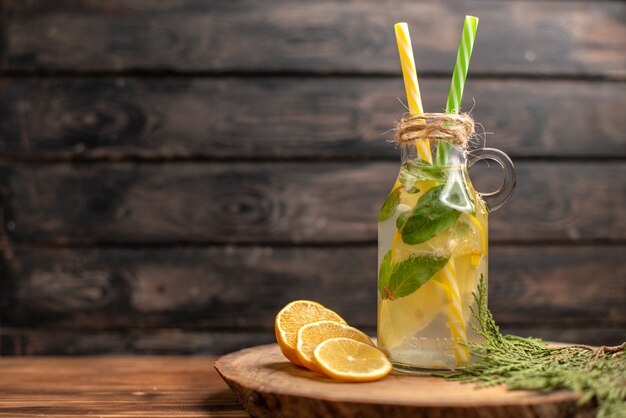 Front view of fresh detox water in a glass served with tubes and lemon limes