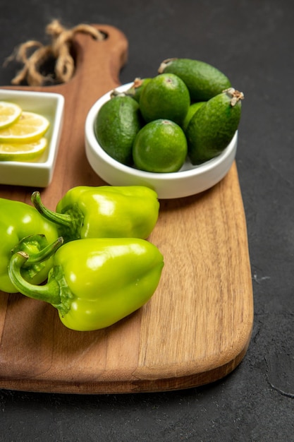 暗い表面のフルーツ健康柑橘類の食事植物に緑のピーマンとレモンと正面図新鮮なフェイジョア
