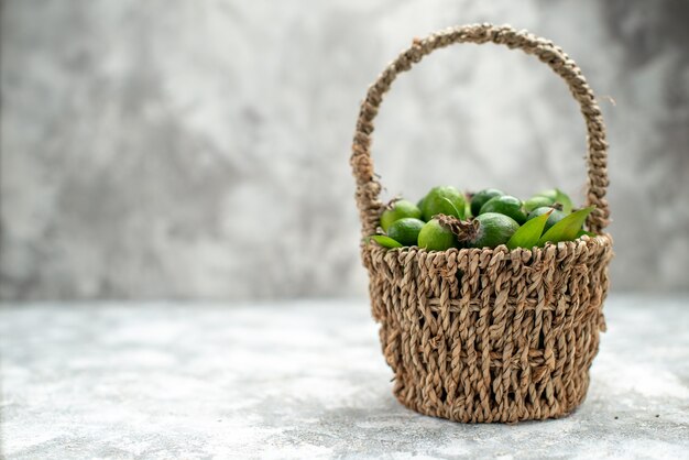 Front view fresh feijoas in wicker basket on grey isolated surface free space