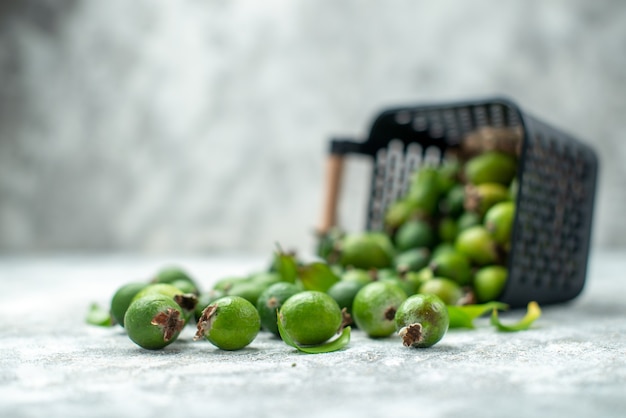 Front view fresh feykhoas scattered from basket on grey isolated surface