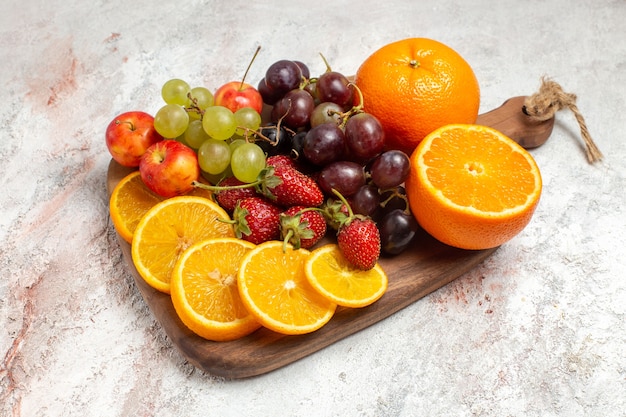 Вид спереди композиция из свежих фруктов апельсины, виноград и клубника на белом пространстве