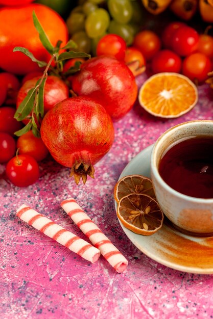 Front view fresh fruit composition with cup of tea on light-pink surface