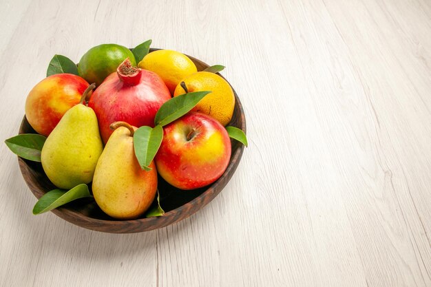 Вид спереди свежие фрукты яблоки груши и другие фрукты внутри тарелки на белом столе фрукты спелое дерево спелые свежие многие
