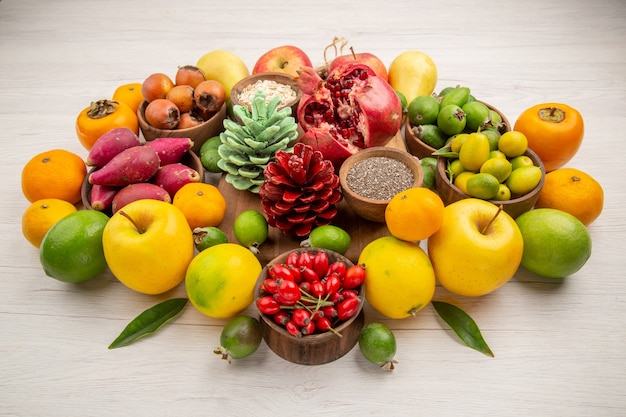 Vista frontale composizione di frutta fresca frutti diversi su sfondo bianco gustosa salute agrume colore bacca dieta esotica