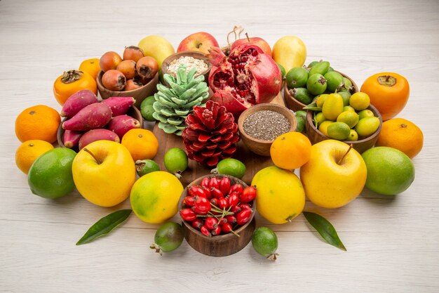Вид спереди свежие фрукты композиция разные фрукты на белом фоне вкусное здоровье цитрусовое дерево цвет ягодная диета экзотика