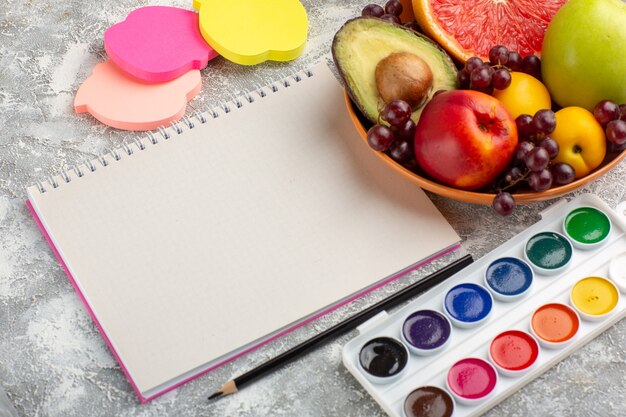 Front view fresh fruits grapes peach and avocado inside plate with notepad on white surface