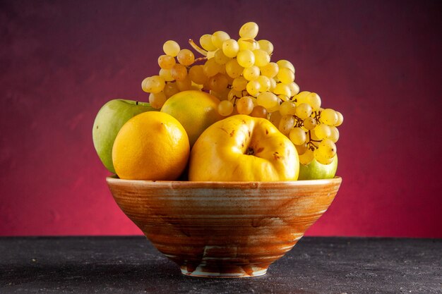 Front view fresh fruits in wooden bowl apples quince lemon grapes on red table