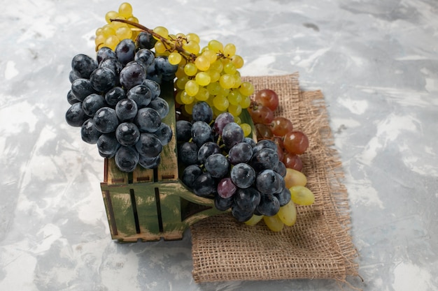 Вид спереди свежий виноград сочные и спелые фрукты на белом столе