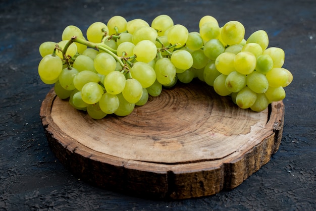 A front view fresh green grapes sour juicy and mellow on the wooden desk and dark background fruit ripe plant green