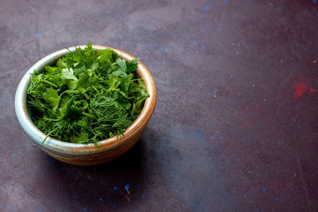 Вид спереди свежая зелень внутри круглой миски на темном столе, зеленые свежие овощные продукты