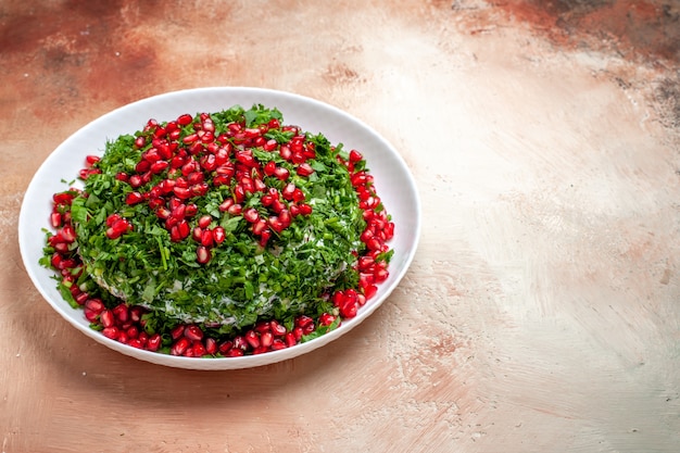 Vista frontale verdure fresche con melograni sbucciati sul tavolo luminoso di colore verde della frutta