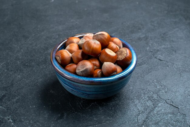 Front view fresh hazelnuts inside little pot on dark surface