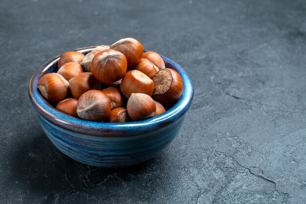 Front view fresh hazelnuts inside little pot on dark surface