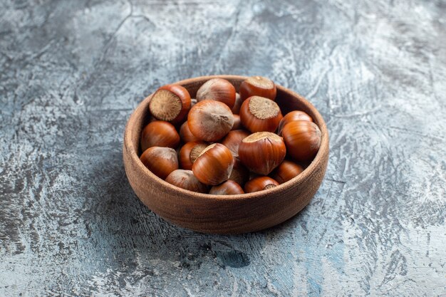 Front view fresh hazelnuts inside plate on white background