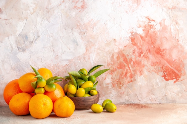 Front view of fresh kumquats in a brown pot and tangerines on colorful bakground