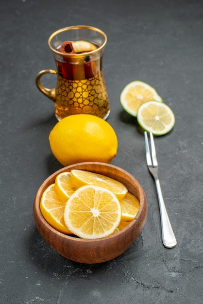 Вид спереди свежие дольки лимона с чаем на темном фоне